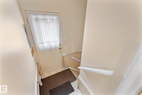 Entryway featuring a white door with a window, light-toned walls, and a white handrail - 15112 76A Avenue, Edmonton, AB 