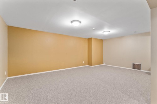 Spacious room featuring light-toned carpeting, neutral wall colors, recessed lighting, and white baseboards - 15112 76A Avenue, Edmonton, AB 