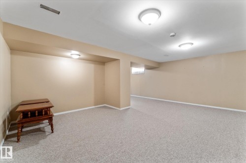 Finished room featuring light neutral wall paint, white baseboards, textured gray carpeting, and overhead lighting fixtures - 15112 76A Avenue, Edmonton, AB 