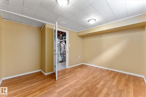 Room featuring wood-finish flooring, neutral wall paint, white baseboards, and a white grid ceiling with recessed lighting - 15112 76A Avenue, Edmonton, AB 