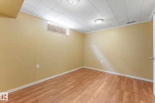 Room featuring wood-finish flooring, light tan walls, white baseboards, and a dropped ceiling with integrated lighting - 15112 76A Avenue, Edmonton, AB 