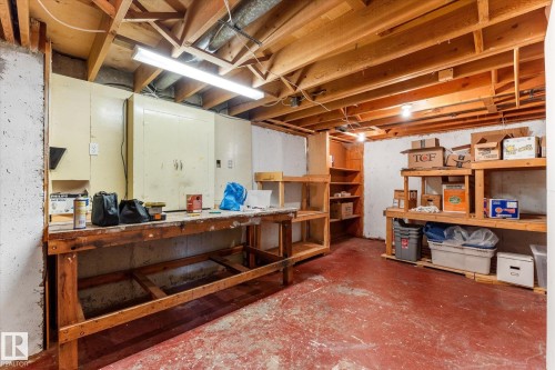 Basement area featuring exposed wood ceiling joists, concrete flooring, and a built-in workbench - 15112 76A Avenue, Edmonton, AB 