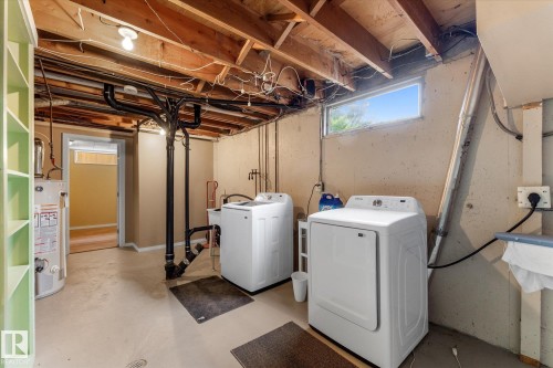 Utility space featuring exposed ceiling joists, a small window, built-in shelving, a water heater, and painted concrete flooring - 15112 76A Avenue, Edmonton, AB 