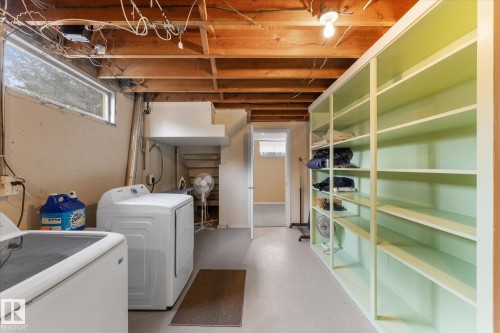 Utility space featuring exposed ceiling joists, concrete flooring, a single window, and extensive built-in shelving units - 15112 76A Avenue, Edmonton, AB 
