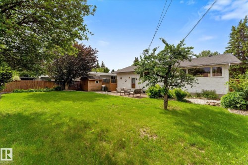Expansive green lawn with mature trees and a private patio area - 15112 76A Avenue, Edmonton, AB 