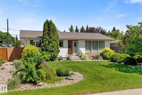 Ranch-style residence featuring a prominent front lawn, mature landscaping, and a fenced side yard - 15112 76A Avenue, Edmonton, AB 