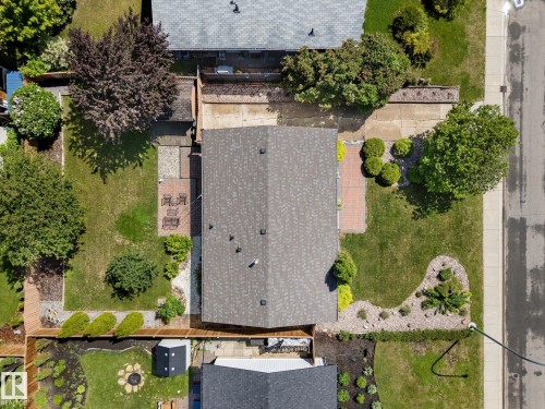 Property featuring a gabled roofline, front and rear green spaces, an integrated driveway, a rear patio, and established perimeter landscaping - 15112 76A Avenue, Edmonton, AB 