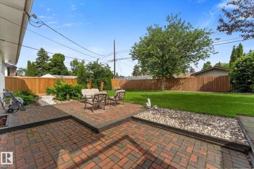 Expansive backyard featuring a brick paver patio, a lush green lawn, and a privacy fence - 15112 76A Avenue, Edmonton, AB 