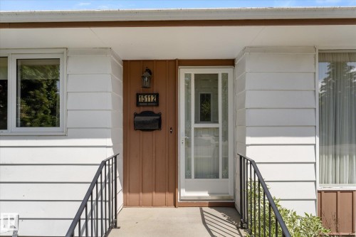 Front entrance featuring white horizontal siding, a brown vertical panel door surround, and a white storm door - 15112 76A Avenue, Edmonton, AB 