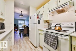 Kitchen featuring white cabinetry with dark hardware, white countertops, a white range with overhead ventilation, and a white refrigerator - 