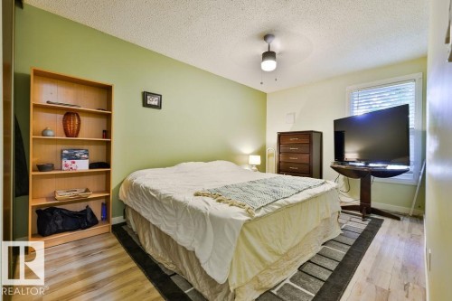 Bright bedroom featuring wood-finish flooring and a light green accent wall - 17009 109 Street, Edmonton, AB 