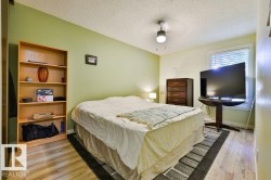 Bright bedroom featuring wood-finish flooring and a light green accent wall - 
