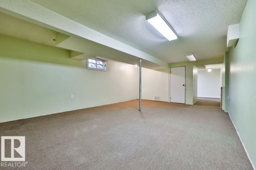 Spacious lower-level area featuring light green walls, exposed ceiling beams, and recessed lighting - 17009 109 Street, Edmonton, AB 