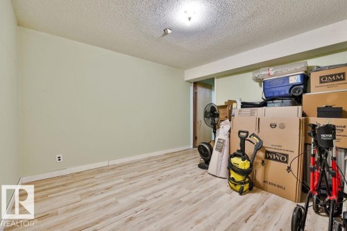Room featuring wood-finish flooring, light green painted walls, white trim, and a popcorn ceiling with an overhead light fixture - 17009 109 Street, Edmonton, AB 