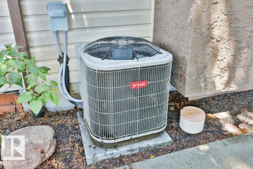 Bryant air conditioning unit on a concrete pad, supported by electrical conduit and wiring - 17009 109 Street, Edmonton, AB 