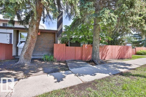 Exterior featuring a concrete walkway, mature trees, and a privacy fence - 17009 109 Street, Edmonton, AB 