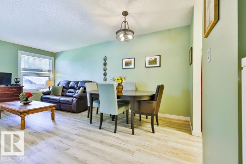 Open concept living area with wood-finish flooring, a contemporary ceiling fixture, and a window with blinds - 17009 109 Street, Edmonton, AB 