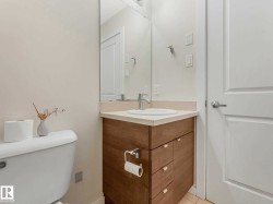 Powder room with a wood-finish vanity, light-colored countertop, and a built-in sink - 