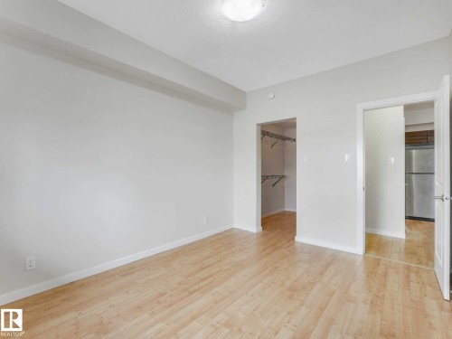 Bright room featuring wood-finish flooring, a flush-mount ceiling light, and a dedicated closet with shelving - 406 9519 160 Avenue, Edmonton, AB 