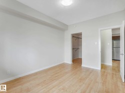 Bright room featuring wood-finish flooring, a flush-mount ceiling light, and a dedicated closet with shelving - 