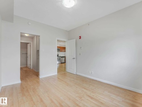 Spacious room featuring light wood-finish flooring, white walls, and a recessed ceiling light fixture - 406 9519 160 Avenue, Edmonton, AB 