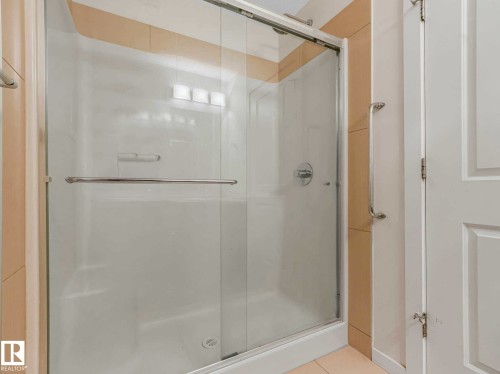 Walk-in shower enclosure featuring a clear glass door with a polished chrome pull handle, a built-in shower niche, and a polished chrome shower faucet - 406 9519 160 Avenue, Edmonton, AB 
