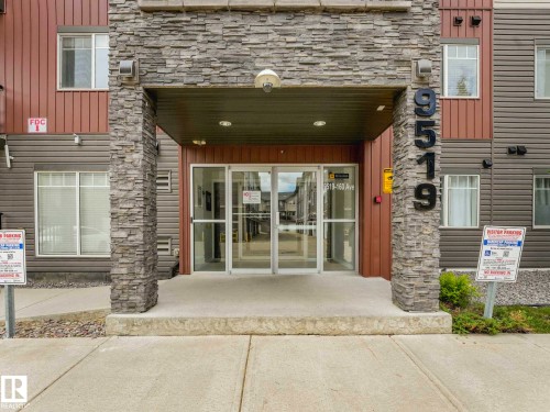 Building entrance featuring a stone facade and glass double doors - 406 9519 160 Avenue, Edmonton, AB 