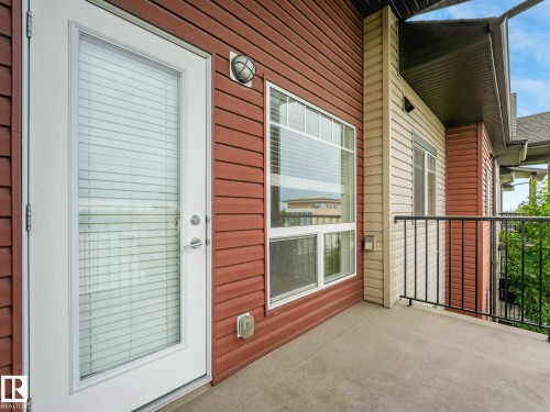 Private balcony featuring concrete flooring, black metal railings, and a glass-paneled door with integrated blinds - 406 9519 160 Avenue, Edmonton, AB 