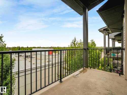 Private concrete balcony featuring a black metal railing and overhead structural support - 406 9519 160 Avenue, Edmonton, AB 