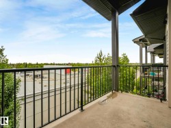Private concrete balcony featuring a black metal railing and overhead structural support - 
