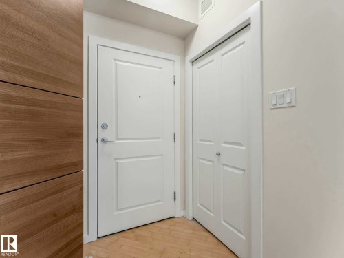 Entryway featuring a paneled door, bi-fold closet doors, light wood-finish flooring, and a contemporary light switch panel - 406 9519 160 Avenue, Edmonton, AB 