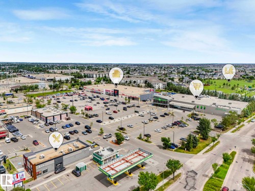 Aerial perspective showcasing a commercial development with multiple retail buildings and extensive paved parking areas - 406 9519 160 Avenue, Edmonton, AB 