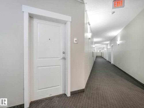 Entry door with panel detailing, white trim, and chrome hardware - 406 9519 160 Avenue, Edmonton, AB 