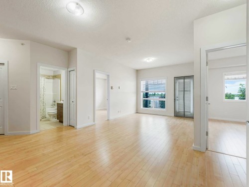 Open concept living area featuring light wood-finish flooring, white walls, and recessed lighting - 406 9519 160 Avenue, Edmonton, AB 