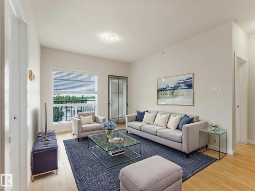 Living area featuring light wood-finish flooring, white walls, and a large window with horizontal blinds - 406 9519 160 Avenue, Edmonton, AB 