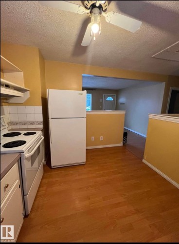 Kitchen featuring wood-finish flooring and a white appliance suite including a refrigerator and electric range - 9209 150 Street, Edmonton, AB 