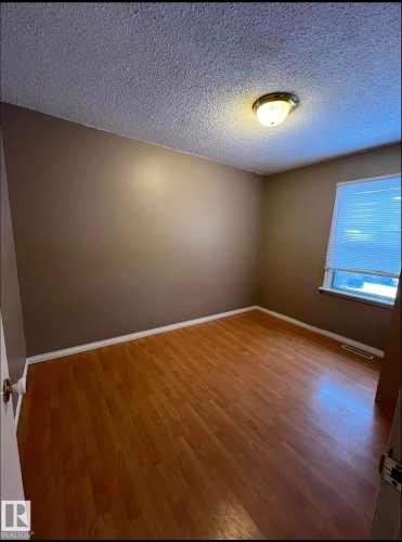 Room featuring wood-finish flooring, a window with blinds, and white baseboards - 9209 150 Street, Edmonton, AB 