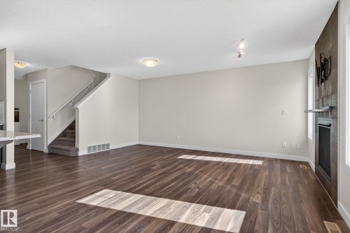 Spacious living area featuring wide plank wood-finish flooring and a contemporary fireplace with a dark tile surround - 5306 67 Street E, Beaumont, AB 