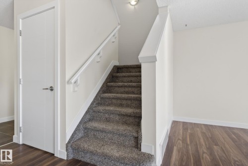 Carpeted staircase with white handrail and trim - 5306 67 Street E, Beaumont, AB 