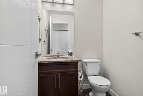 Bathroom featuring a dark wood vanity with a stone countertop, an undermount sink, and a modern rectangular mirror - 5306 67 Street E, Beaumont, AB 