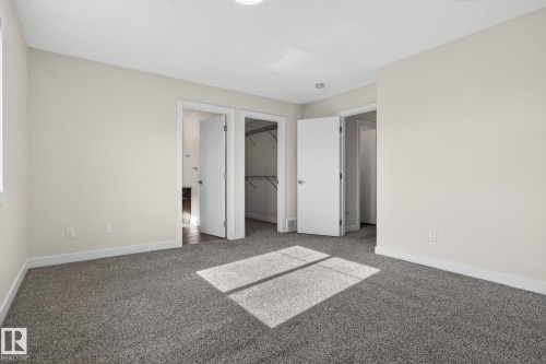 Spacious room featuring neutral carpeting, light-toned walls, and white trim - 5306 67 Street E, Beaumont, AB 