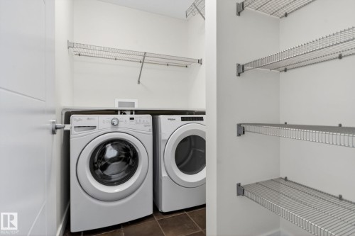 Dedicated laundry area featuring a front-loading washer and dryer, wire shelving, a hanging rod, and tile flooring - 5306 67 Street E, Beaumont, AB 