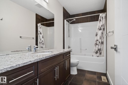 Bathroom featuring a built-in vanity with dual sinks, a light-toned countertop, and dark wood-finish cabinetry - 5306 67 Street E, Beaumont, AB 