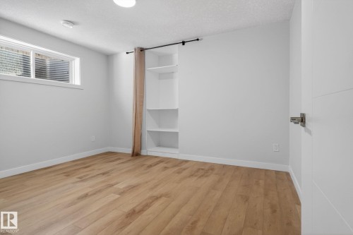 Room featuring wood-finish flooring, white baseboards, and a built-in shelving unit - 5306 67 Street E, Beaumont, AB 