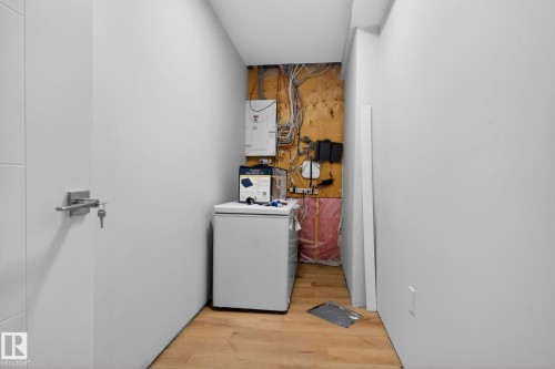 Utility area featuring wood-finish flooring and a white door with a contemporary brushed nickel handle - 5306 67 Street E, Beaumont, AB 