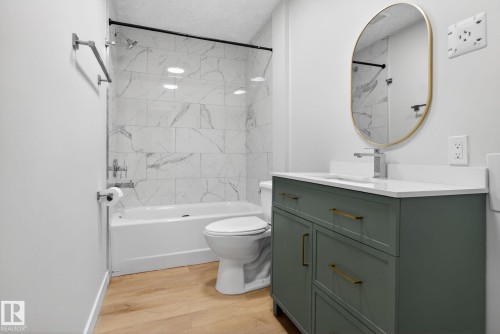 Bathroom featuring a green vanity with brass hardware, a white countertop, and an oval mirror with a gold frame - 5306 67 Street E, Beaumont, AB 