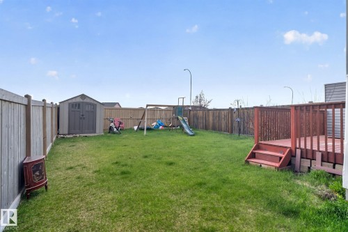 Expansive backyard featuring a large grass area, a dedicated storage shed, and a wooden deck with steps - 5306 67 Street E, Beaumont, AB 