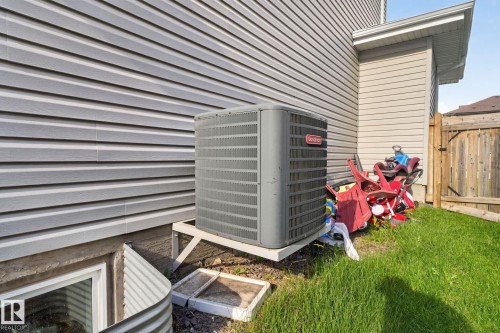 Gray horizontal siding exterior with a ground-level window well and a wooden fence - 5306 67 Street E, Beaumont, AB 