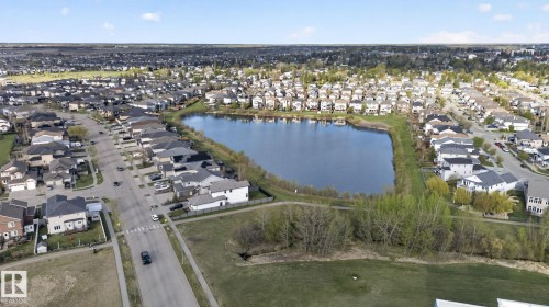 Aerial perspective showcasing a residential area with a prominent central lake, surrounded by various homes - 5306 67 Street E, Beaumont, AB 