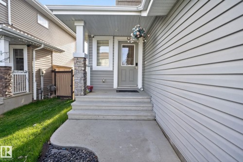 Welcoming front entry with stone-wrapped columns, a covered porch, and light gray siding - 5306 67 Street E, Beaumont, AB 